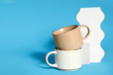 Mavi zemin üzerinde farklı seramik bardaklara sahip dekoratif podyumlar