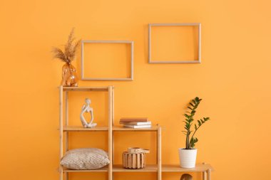 Raf ünitesi ve boş fotoğraf çerçeveleri sarı duvarda