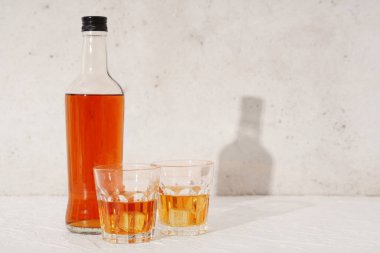 Beyaz zemin üzerinde buz küpleri olan bir şişe rom.