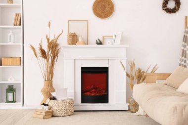 Şömineli, kanepeli ve kış dekorlu oturma odasının içi aydınlık.