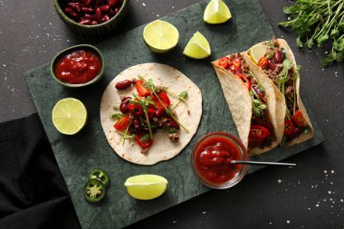 Taze takolu tepsi ve siyah benekli arka plandaki malzemeler.