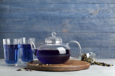 Çaydanlık ve bir bardak kelebek arkaplanda bezelye çiçeği çayı.