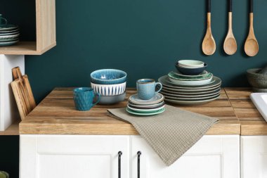 Mutfakta mavi duvarın yanında farklı tabaklar olan tahta masa.