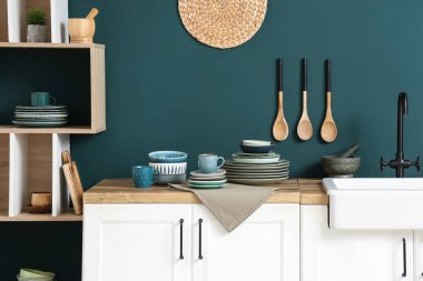 Mutfağın içinde mavi duvarın yanında farklı plakalı tezgahlar var.