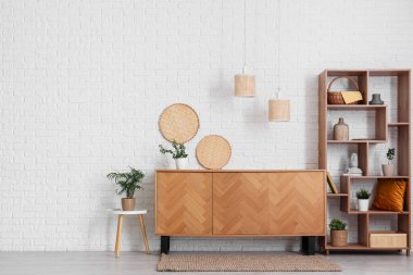 Odanın içinde ahşap tuvalet, raf ünitesi ve bitkiler var.