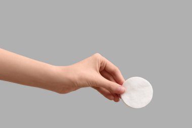 Gri arkaplanda pamuk yastıklı kadın eli