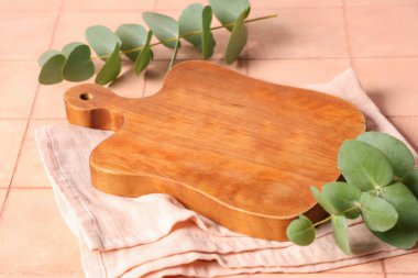 Peçete ve okaliptüs dallı boş kesme tahtası Pembe döşemeli masa, yakın plan