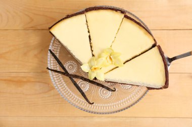 Tahta arka planda tatlı vanilyalı cheesecake parçalarıyla dur.