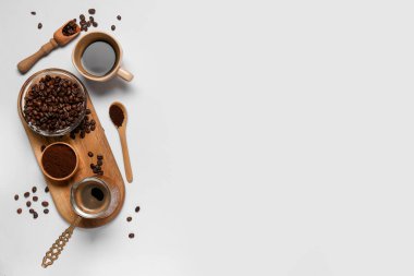 Bir fincan kahve, bir kase toz ve beyaz arka planda fasulye.