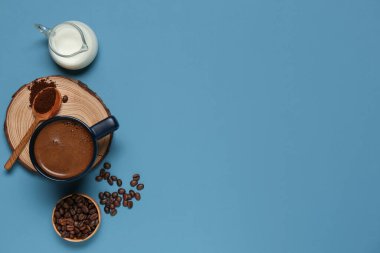 Mavi arka planda bir sürahi sütlü ve fasulyeli kahve.