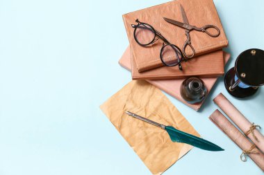 Kitap, kalem, mürekkep hokkası, parşömen ve makaslı mavi arkaplan