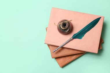 Yeşil arkaplanda ucu kalem ve mürekkep hokkası olan kitaplar