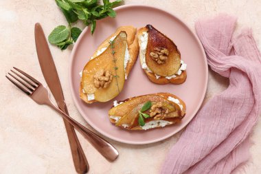 Bej arka planda ricotta peynirli ve cevizli armut bruschetta tabağı.