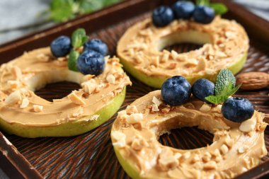 Lezzetli elma turlu ahşap tepsi, fındık ezmesi, yabanmersini ve nane yaprağı, yakın plan.