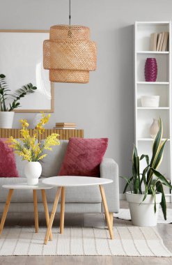 Modern oturma odasının içinde raflar, sehpalar ve kanepede mor yastıklar.