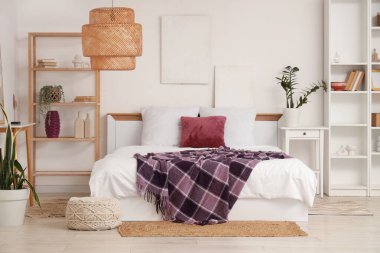 Yatağında raf üniteleri, ev bitkileri ve mor battaniye olan modern yatak odası.