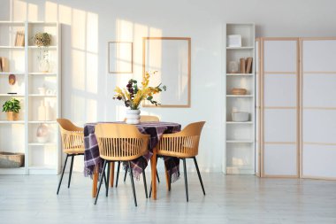 Yemek odasının içinde güzel çiçekler ve şık mor kumaşlar var.