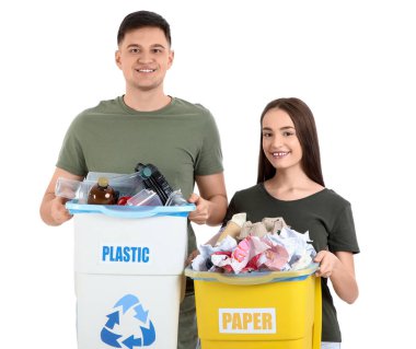 Çöpleri beyaz arka planda çöp kutularına ayıran genç bir çift. Küresel Geri Dönüşüm Günü