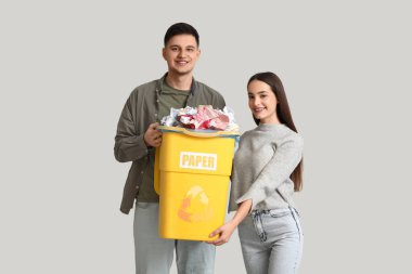 Beyaz duvarın yanındaki çöp kutusunda çöpleri ayıran genç bir çift. Küresel Geri Dönüşüm Günü