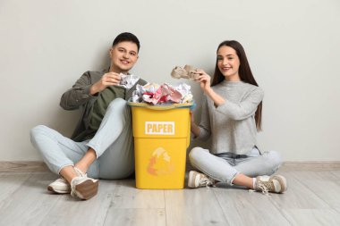 Çöp tenekesinde beyaz duvarın yanında oturan genç çift. Küresel Geri Dönüşüm Günü