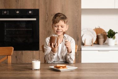 Mutfakta bir kavanoz çikolata ezmesi olan tatlı bir çocuk.