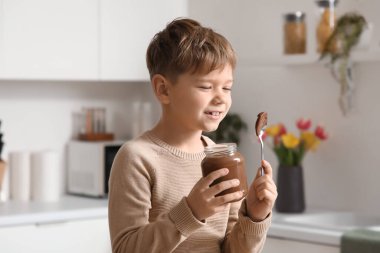 Mutfakta bir kavanoz çikolata ezmesi olan tatlı bir çocuk.