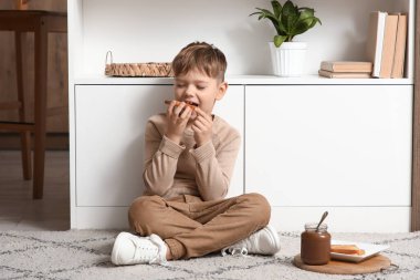 Mutfakta çikolata ezmeli tost yiyen tatlı küçük çocuk.