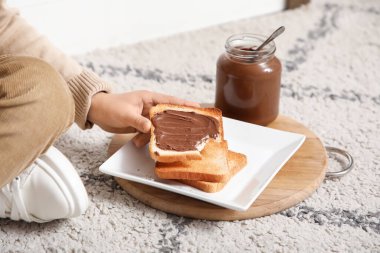 Isırılmış tostu ve tatlı çikolata ezmesiyle küçük çocuk, yakın plan.