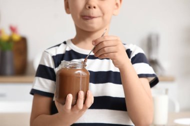 Mutfakta bir kavanoz çikolata ezmesi olan sevimli küçük çocuk, yakın plan.