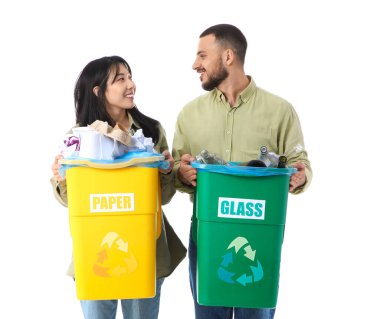 Çöpleri beyaz arka planda çöp kutularına ayıran genç bir çift. Küresel Geri Dönüşüm Günü