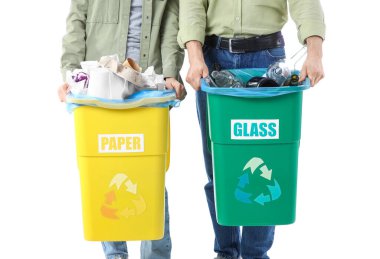 Çöpleri beyaz arka plandaki çöp kutularına dizilmiş genç bir çift, yakın plan. Küresel Geri Dönüşüm Günü