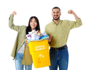 Çöpleri çöp kutusuna atıp beyaz arka planda kaslarını gösteren genç bir çift. Küresel Geri Dönüşüm Günü