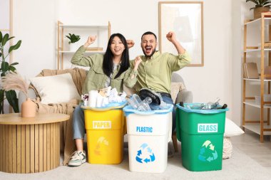 Evdeki çöp bidonlarını ayıran mutlu genç çift. Küresel Geri Dönüşüm Günü