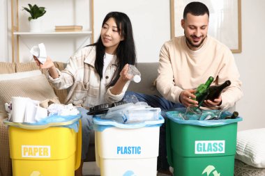 Evdeki çöp bidonlarını düzenleyen genç bir çift. Küresel Geri Dönüşüm Günü