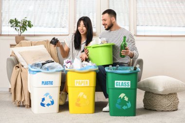 Evdeki çöp bidonlarını düzenleyen genç bir çift. Küresel Geri Dönüşüm Günü