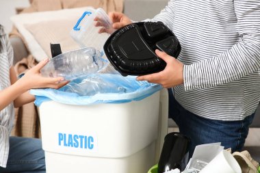 Evdeki çöp kutusunda çöpleri ayıran genç bir çift, yakın çekim. Küresel Geri Dönüşüm Günü