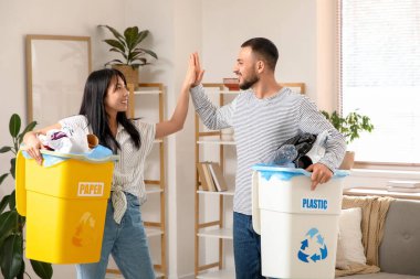 Çöpleri çöp tenekelerinde toplayan genç bir çift evde beşlik çakıyor. Küresel Geri Dönüşüm Günü