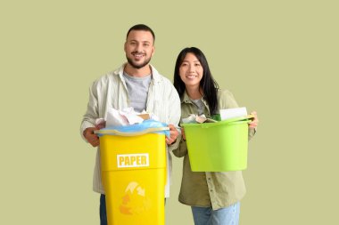 Çöpleri yeşil arka planda çöp kutularına ayıran genç bir çift. Küresel Geri Dönüşüm Günü