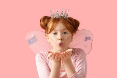 Peri kostümlü tatlı kız pembe arka planda öpüşüyor.