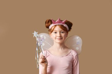 Kahverengi arka planda sihirli değneği olan peri kostümlü tatlı kız.