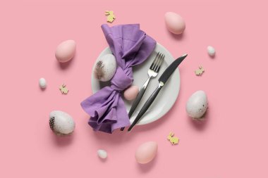 Paskalya yumurtaları ve pembe arka planda tahta tavşanlarla güzel bir masa.
