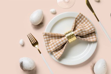 Paskalya yumurtaları ve bej arka planda tüyleri olan güzel bir masa.