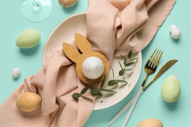 Paskalya yumurtaları ve turkuaz arka planda okaliptüs dallarıyla güzel bir masa.