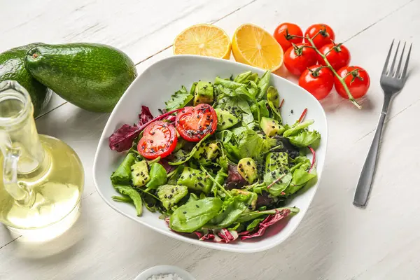 Çeri domatesli avokado salatası ve beyaz ahşap arka planda limon.