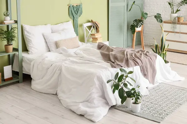 Yatak odasının içinde katlanmış ekran ve yeşil bitkiler.