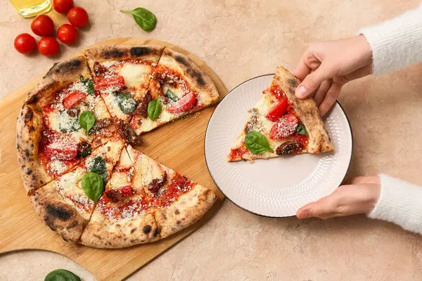 Bej arka planda Margarita 'lı pizza tabağı olan kadın elleri. Yakın çekim.