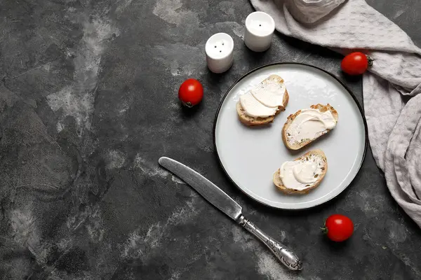 İşlenmiş peynirli lezzetli bruschetta tabağı ve siyah arka planda taze domates.
