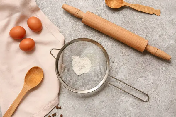 Un, kaşık, merdane ve grunge arkaplanda tavuk yumurtası olan metal elek.