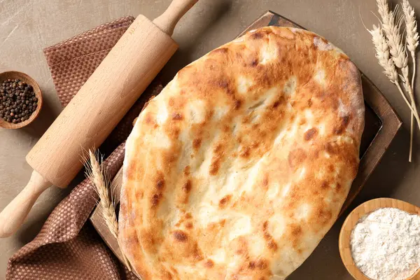 Lezzetli lavaşlı ahşap tepsi, merdane, biber ve kahverengi grunge arka planda un.