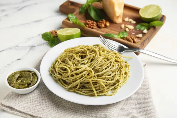 Lezzetli soslu makarna tabağı, bir kase sos ve mermer zemin üzerine malzemeler.